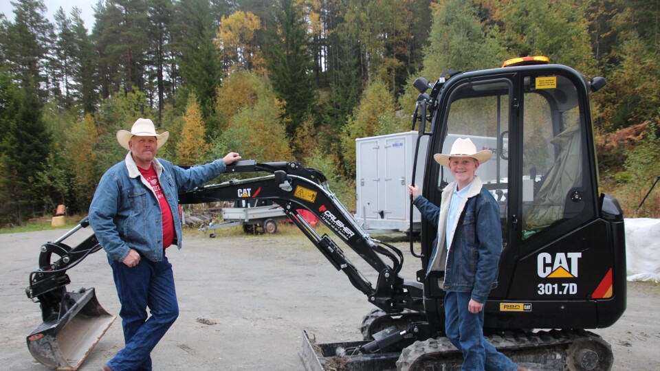 Christoffer og pappa Lloyd Sundstøl viser konfirmasjonsgaven, en Cat 301.7D.