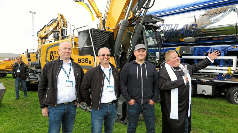 SIGNINGEN: Maken til maskinoverrekkelse skal man lete lenge etter. Fører Jonas Nyborg (nr. 3 fra v.) hadde tatt med seg vennen Svein Erik Morken som i anledning av forestående giftemål hadde laget sin egen prestedrakt med megakors for å trene på seremonien. Hans prising av Liebherr-beltegraveren med påmontert boreaggregat vakte stor oppmerksomhet og munterhet. Fra v. Liebherrs Eivind Engan og Roy Haslegård.