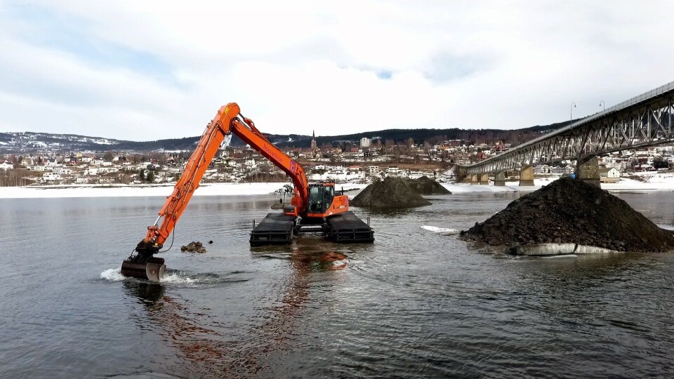 Waterking graver grøft for nye vann- og avløpsledninger like ved Vingnesbrua mellom sentrumssiden i Lillehammer og Vignes. Lillehammer skimtes i bakgrunnen.