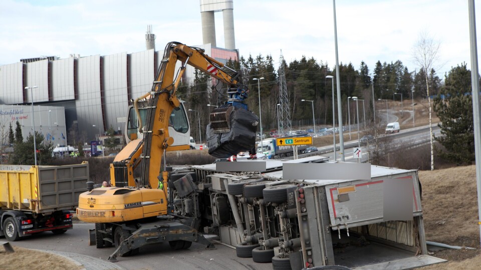 Den veltede tralla ble tømt med en materialhåndterer. Avfallsforbrenningsanlegget, Klemetsrudanlegget AS, i bakgrunnen.