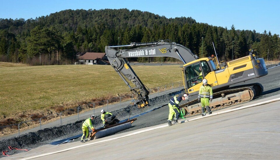Maskin drar rullen med duk og mannskap styrer utleggingen.