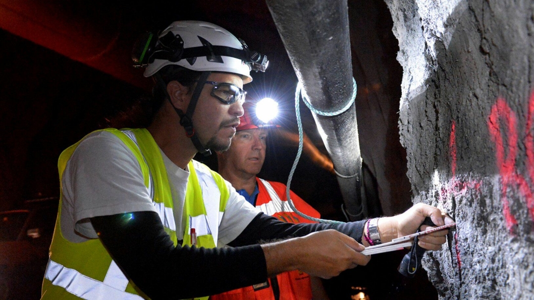 Jozset Hecht Mendez fra bedriften Amberg Technologies sjekker ett av de 24 hullene som ble boret inn i tunnelveggen. Kontrollingeniør Hallvor Brekke fra Statens vegvesen er med for å lære mer om å bruke seismikk i tunneldriving.