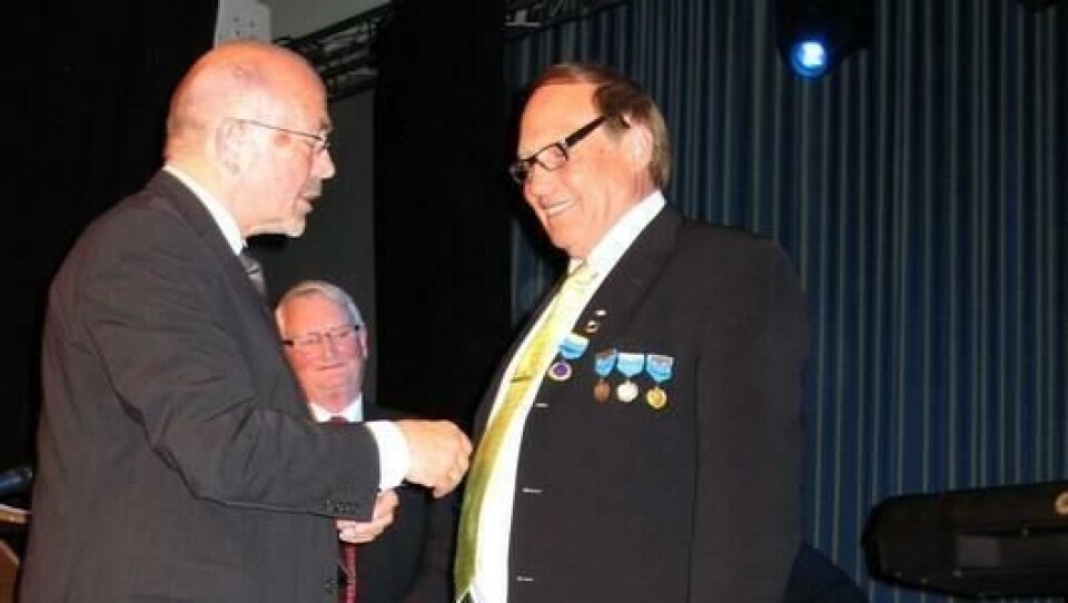 Per Madsen fester NLFs høyeste utmerkelse som innebærer æresmedlemskap, på brystet til Erik Graarud. En smilende Edvin Bellsli i bakgrunnen ble noen minutter senere også utnevnt til æresmedlem i NLF.