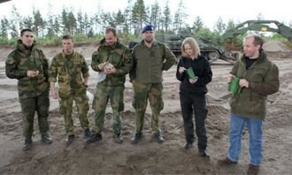 Tid for lunsj. Grenader Olsen (f.v.), Sersjant Strand og Fenrik Flatla spiser brødmat. Løytnant Jakobsen spiser nøtter (som han gjemmer på ryggen). Gina og Ernst Morten får prøve feltrasjoner, med en viss skepsis.