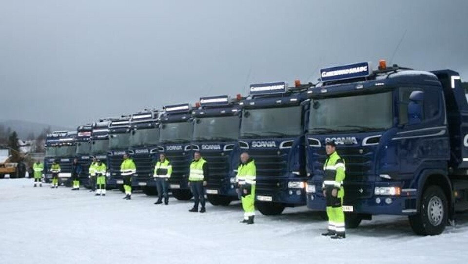 Sjåfører og biler på rekke og rad hos Gjermundshaug. De nyeste bilene står parkert nærmest kamera.