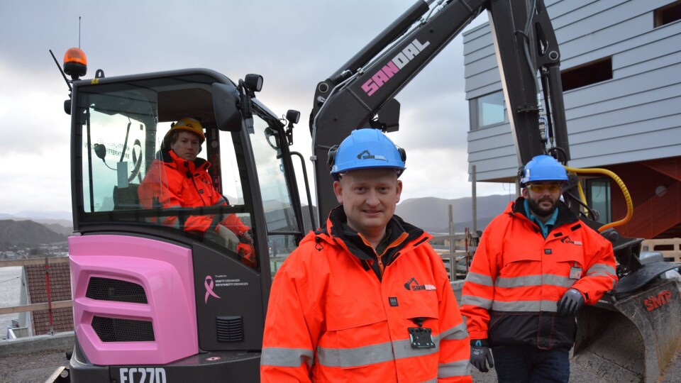Entreprenørselskapet Geir Sandal AS, med Joakim Sandal (midten) i spissen, har valgt en utradisjonell farge på sin nyeste gravemaskin. Meningen med stuntet er at tjue prosent av inntektene maskinen generer det neste året, skal gå til forskning på brystkreft. F.v.: Tor Martin Refvik, Joakim Sandal og Rune Eriksen.