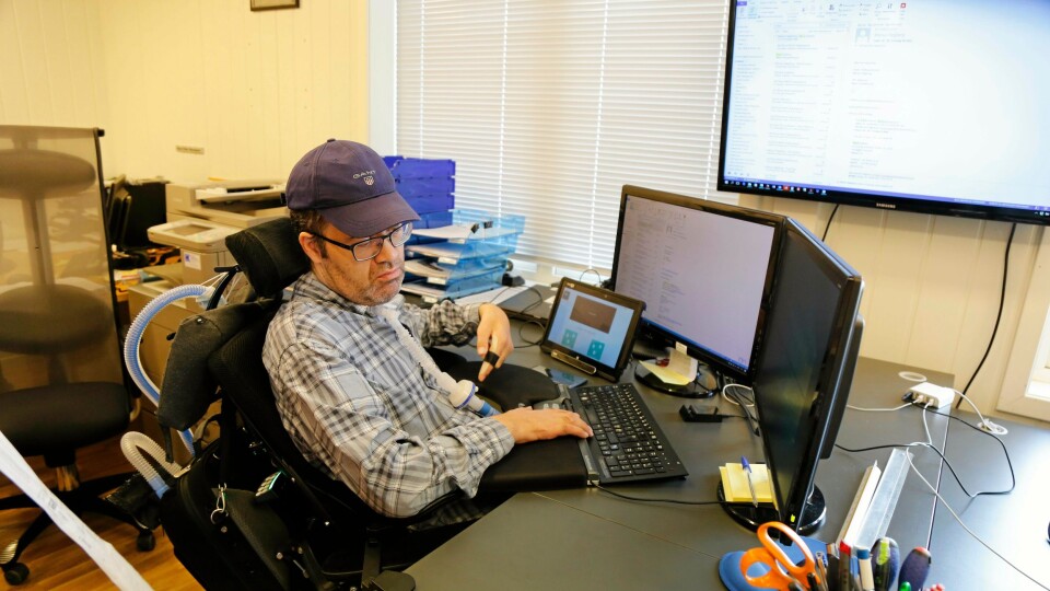 Arbeidsplassen til Bjørn Åge Misund. Den lille skjermen bruker han til å kommunisere med, de to større er arbeidsskjermene hans og på veggen ser de andre ansatte hva han driver med. På rullestolen hans henger respiratoren som pumper luft inn i Bjørn Åge via slangen i halsen.