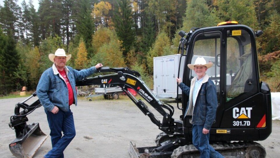 Christoffer og pappa Lloyd Sundstøl viser konfirmasjonsgaven, en Cat 301.7D. Foto: Gyril Sundstøl