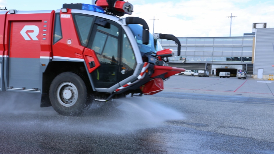 Brannbil vanner varm asfalt på Oslo Lufthavn. Bildet er fra vanning sommeren 2014, på samme måte som det gjøres denne sommeren.