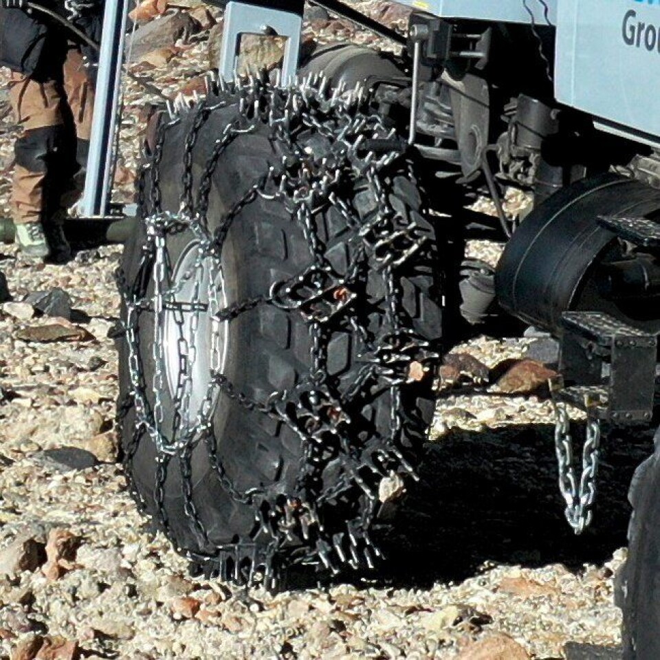 Kjettingene på bakhjulene på den ene Unimog-en fungerer dårlig på vei, men gir godt grep i det bratte terrenget med stein, grus, snø og is på fjellet Ojos del Salado i Chile.