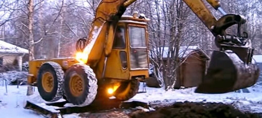 Uvanlig gravemaskin heiser hjulene ved gravearbeid