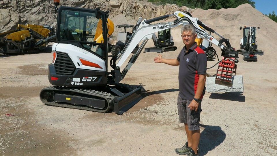 STOLT: Daglig leder Per Gunnar Holmgren med bestselgeren Bobcat E27 med en kraftig steinblokk i klypa og mindre maskiner som bakgrunn.