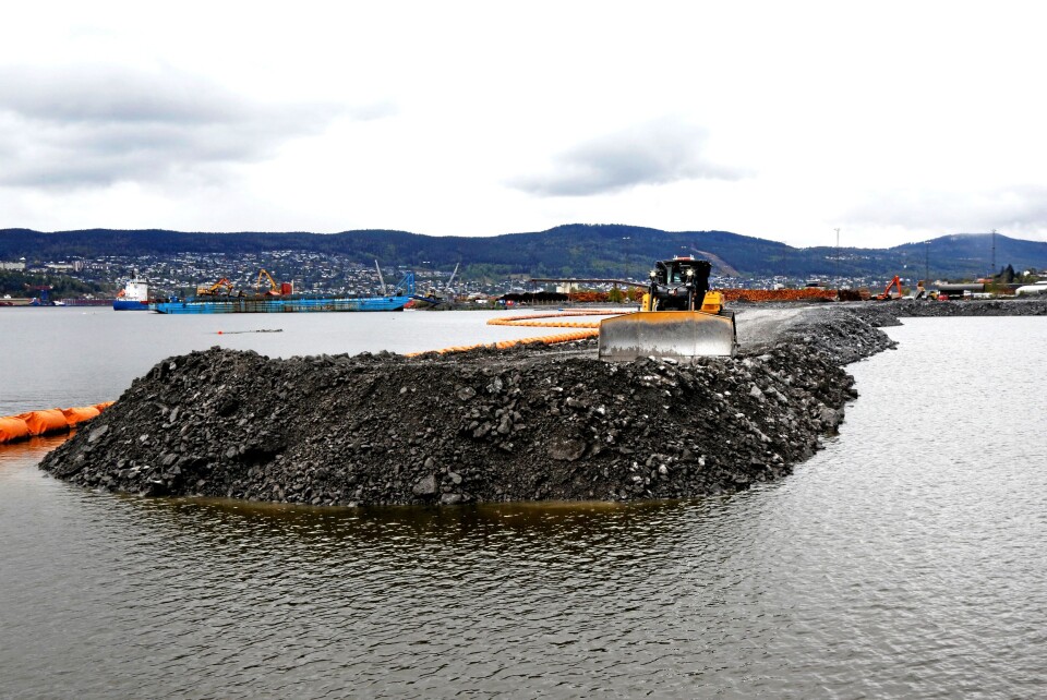SPEKTAKULÆRT: Den splitter nye Cat D6 XE-dozeren skyver stein ned i vannet. På taket er det livbøye med line som løsner om maskinen går under vann, og i hytta er det dykkerutstyr til føreren.