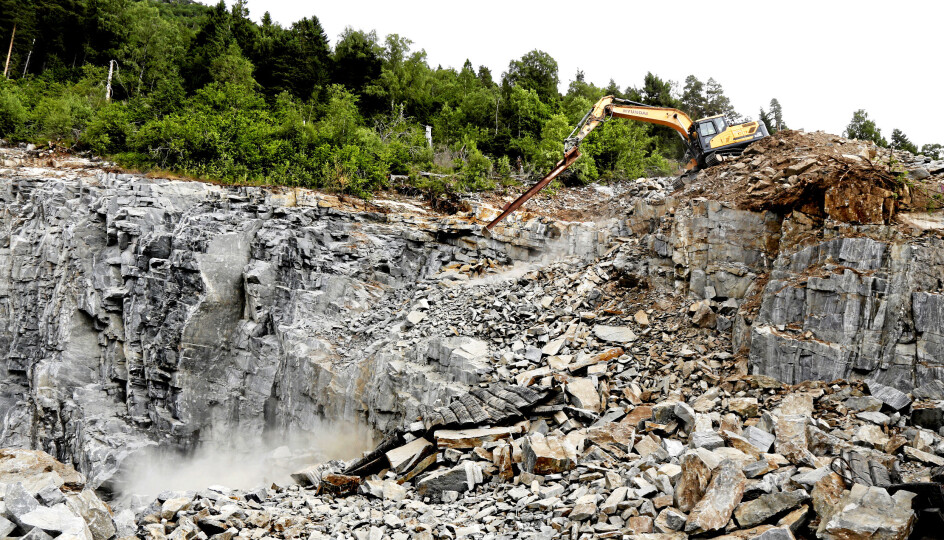 SPEKTAKULÆRT: Med forlengeren i stikka på Hyundai-maskinen, skyver Per Olav Løset løs sprengstein ned skråningen og renser fjellet til neste salve.