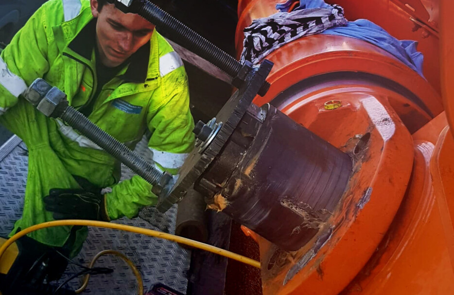 Her er verksmester Johan Gundersen, Sigurd Furulund Maskin, i ferd med å presse ut enav de fremre boltene, der stemplene er festet i bommen. På bildet ser man det for anledningen komponerte avdragersystemet som var med på å rikke løs bolten.