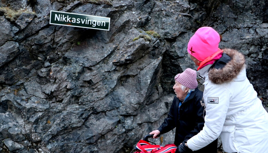 Nikoline Myren Grønning og fylkesordfører Tove-Lise Torve foran skiltet som viser at svingen ved Stigfossen for alltid skal hete Nikkasvingen, til ære for henne og de andre anleggskokkene som var med og bygget Trollstigen.