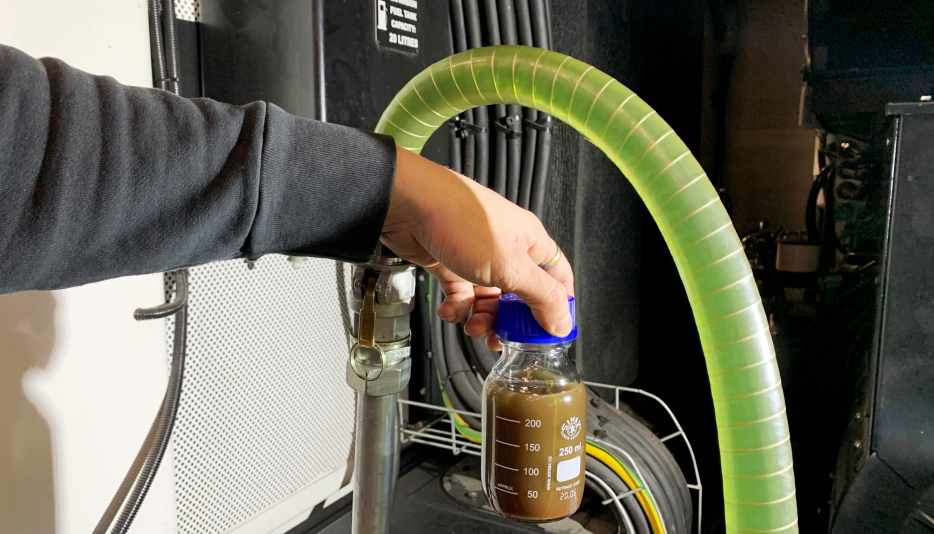 MYE SKITT: Flasken viser innholdet fra denne tanken, pumpet ut før renseprosessen. Anleggsdieselen i slangen er i renseprosess.