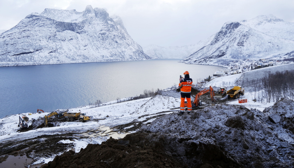 MAKELØST: Utsikten fra toppen i prosjektet er så vill at selv Trond Pettersen som har vært der mange ganger før, måtte hente frem mobiltelefonen og forevige øyeblikket. Kaianlegget skal etableres der man skimter en gravemaskin i vannkanten. Til høyre er en 500 meter gabionmur som beskytter bygda Fjorgård fra fjellets vrede. Foto: Klaus Eriksen