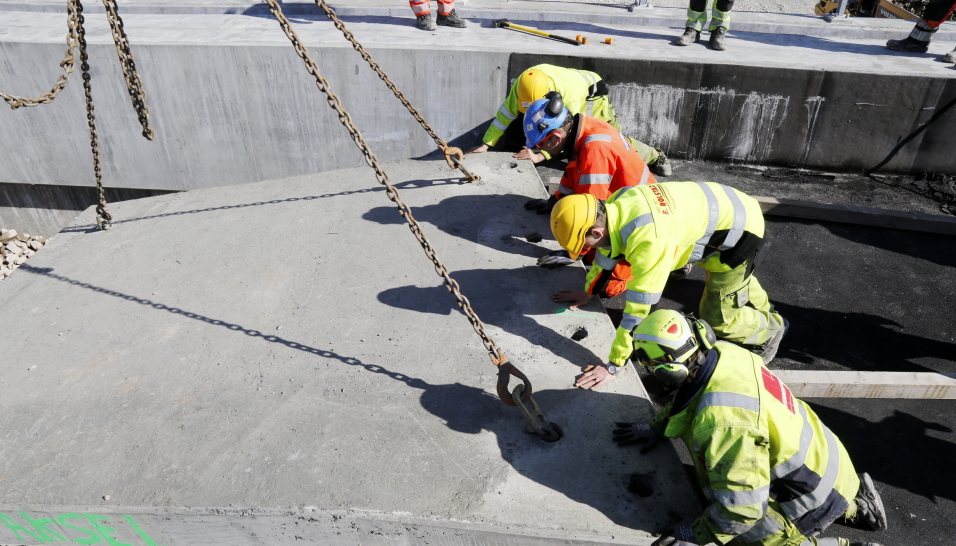 DER: Gjengen ser gjennom hullene i betongplaten og finner stagene som sitter i brukonstruksjonen. Deretter senkes den 10 tonn tunge platen ned. Foto: Klaus Eriksen