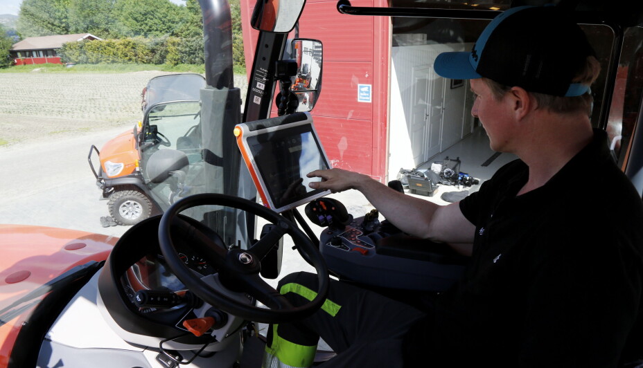 TRYKKER TIL: - Jeg elsker gadgets, sier Petter Pilgaard og går løs på den store skjermen i hytta på Kubota-traktoren. Foto: Klaus Eriksen