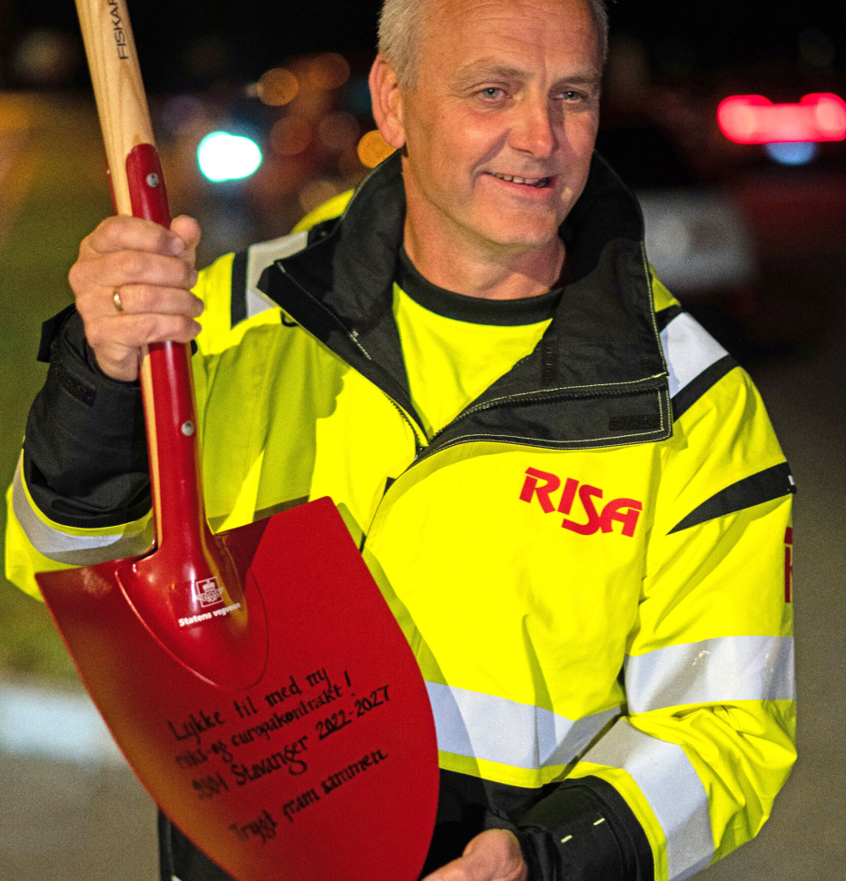 Veidriftssjef Erlend Aksnes i Risa AS, med spaden med påskriften «Lykke til med ny riks- og europavegkontrakt! 9301 Stavanger 2022-27. Trygt fram sammen». Sistnevnte er et av Vegvesenets slagord, og navnet på en Vegvesenets nasjonale kampanjer for trafikksikkerhet.