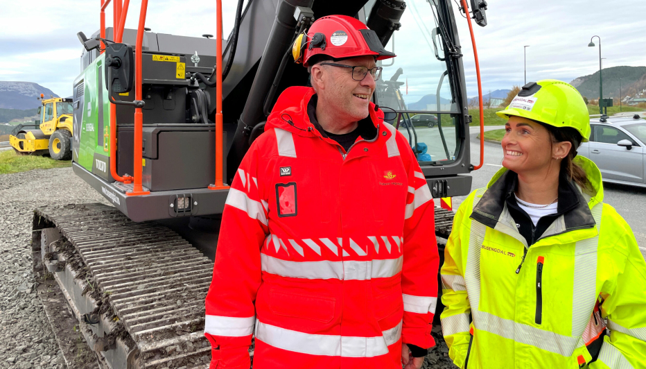 Ingar Valbø, byggeleder i Statens vegvesen og Kamilla Busengdal, prosjektleder i Busengdal AS foran Sunnmøres etter sigende største elektriske gravemaskin.