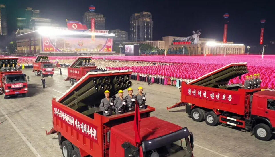 LURERI: Falske tippbiler med rakettsystemer under planet ble vist i paraden. Arbeidere med kjeledresser, gule hjelmer og automatvåpen var plassert på bilene.