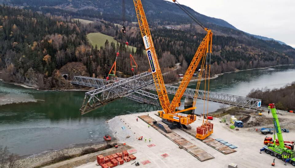 LØFT: Liebherr-krana løfter her det ene av de to bruelementene som havnet i Lågen i flommen etter uværet Hans tidligere i år. Det andre skal også løftes opp denne uken.