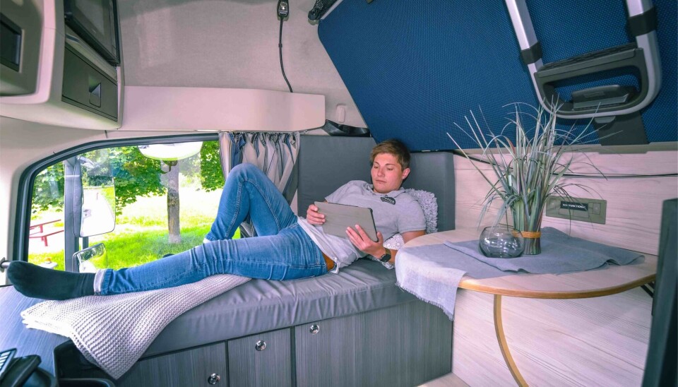 SOFA: Det er en sjeselong/sofa/seng på høyre side i førerhuset. Oppe til venstre skimtes skimtes mikrobølgeovnen. Oppe til høyre er den nedfellbare sengen.